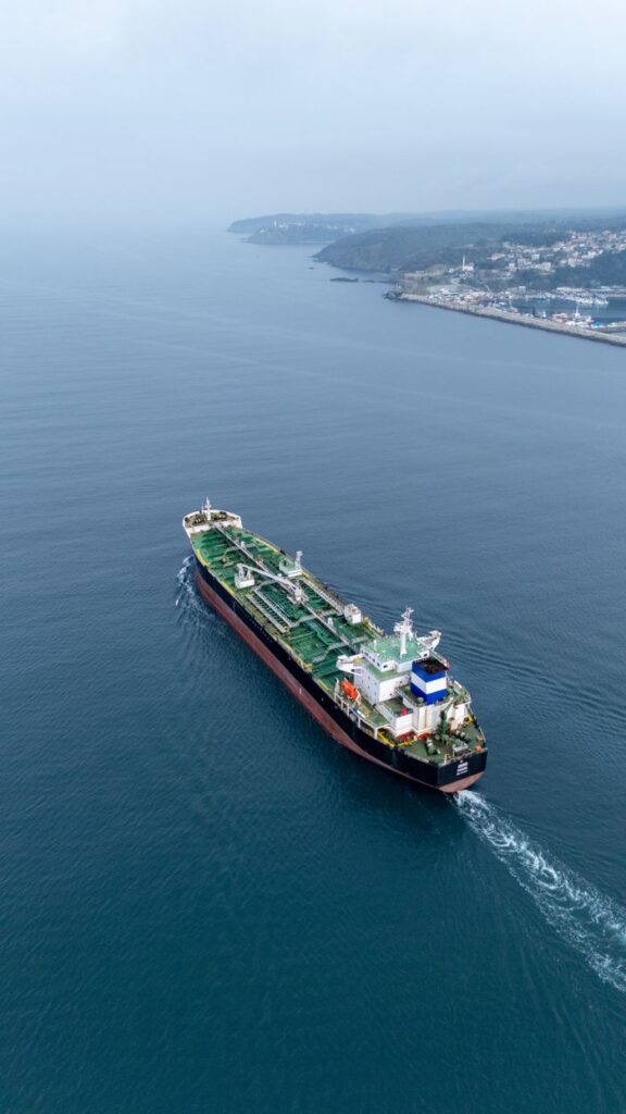 Aerial view of a cargo ship sailing near the coastline on a calm day.